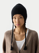 Person wearing a black knit beanie with ear flaps on a white background #color_black