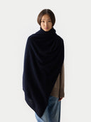 Woman wrapping a dark blue shawl over a brown sweater and jeans on a white background #color_navy-blazer