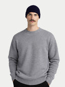 Man wearing a gray sweater and navy beanie on a light gray background #color_navy-blazer