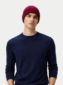 Man wearing a dark blue sweater and red beanie on a white background