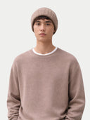 Person wearing a beige knit beanie and sweater on a white background #color_taupe