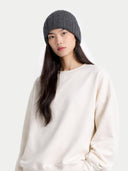 Woman wearing a gray knit beanie and white sweater on a light gray background #color_charcoal