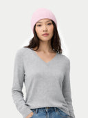 Woman wearing a gray sweater and pink beanie on a white background #color_almond-blossom