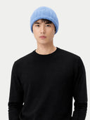Person wearing a blue beanie and black sweater on a white background #color_blue