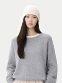 Person wearing a gray sweater and white beanie on a light gray background  #color_off-white