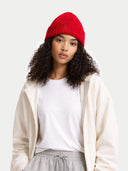 Person wearing a red beanie, white shirt, beige jacket, and gray pants on a light gray background #color_chili-pepper