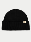 Black beanie with a small logo tag on a light gray background #color_black