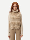 A woman wearing a beige loop-stitch gilet with fringe detail and a necktie, paired with beige leather pants. #color_warm-grey