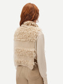 back view of a beige loop-stitch gilet with fringe detail and a necktie, paired with beige leather pants. #color_warm-grey