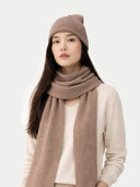 Woman wearing a beige knit hat and scarf on a white background #color_taupe