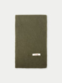 Green knitted scarf with a brand label on a light gray background #color_avocado