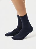 Navy blue ribbed socks worn by a person on a white background #color_navy-blazer