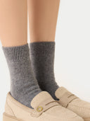 close up of gray socks worn with beige shoes on a neutral background #color_dim-gray