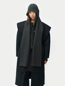 Person wearing a long black coat and black gray hooded scarf on a white background #color_black