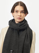A person wearing an oversized cashmere woven scarf in gray color.