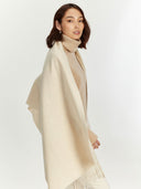 side view of a woman wearing a beige scarf and turtleneck on a white background