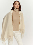 front view of a woman wearing a beige turtleneck sweater and scarf on a white background