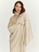 Woman wearing a beige turtleneck sweater and a matching shawl on a white background Woman wearing a beige sweater and holding a beige scarf against a white background