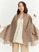 front view of a woman wrapping a beige scarf with fringes on a white background