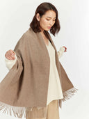 Woman wearing a beige scarf with fringe on a white background