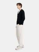 side view of a Man wearing a black cardigan, white pants, and white sneakers on a light gray background #color_black
