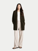 Woman wearing a dark green cardigan over a white top and beige pants on a white background #color_avocado