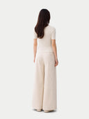 back view of a woman wearing a white outfit with wide-leg pants on a white background #color_whisper-white