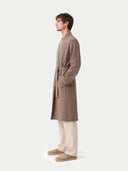 side view of a man wearing a brown robe standing against a white background #color_taupe