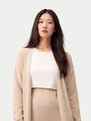 Woman wearing a beige cardigan over a white top and beige pants on a light gray background #color_beige