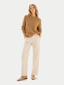 Woman wearing a brown sweater and beige pants on a white background #color_almond