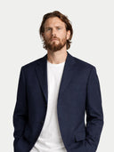 close up of a man wearing a navy blazer over a white shirt on a light gray background #color_navy