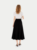 back view of a woman wearing a white top and black skirt on a white background #color_black