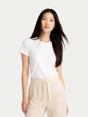 Woman wearing a white t-shirt and beige pants on a plain background #color_off-white