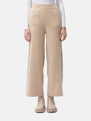 A pair of beige wide-leg cashmere pants, viewed from the side with the wearer facing forward. The pants have a loose and flowing fit with a high waist. #color_beige