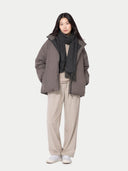 Person wearing a gray coat, scarf, and beige pants on a white background