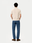 back view of a man wearing a beige shirt with collar and blue jeans on a white background #color_marshmallow