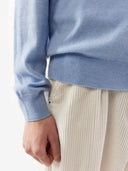 Close-up of a man wearing a light blue cashmere V-neck sweater and beige corduroy pants showing fabric texture and fit. #color_light-blue