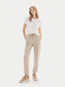 Woman wearing a white t-shirt and beige pants on a white background #color_toasted-almond