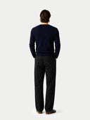 Back view of a person wearing a navy sweater and dark pants on a white background #color_navy-blazer