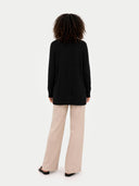 Back view of a person wearing a black sweater and beige pants on a white background #color_black