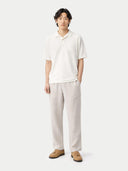 Person wearing a white polo shirt and beige pants on a white background #color_whisper-white