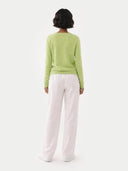 back view of Person wearing a light green sweater and white pants on a white background #color_jade-lime