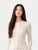 Woman wearing a beige white cardigan against a white background #color_whisper-white