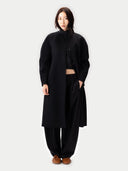 Person wearing a black coat and pants on a white background #color_black