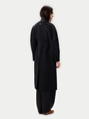 Back view of a person wearing a black coat and pants on a white background #color_black