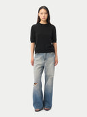 front view of a woman wearing a black crew neck, short-sleeve sweater and blue jeans on a white background #color_black