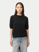 close up front view of a woman wearing a black short-sleeve, crew neck sweater top and light blue jeans on a white background #color_black