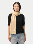 Woman wearing a beige scarf, black top, and jeans on a white background #color_beige