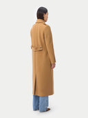 back view of a woman wearing a long beige coat on a white background  #color_almond