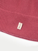 Close-up of a ribbed knit fabric with a brand label on a white background #color_madder-brown